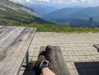 Low section of female legs wearing hiking boots relaxing on mountain