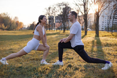 Side view of friends exercising on field