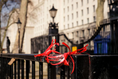 Close-up of red tied to metal railing against buildings in city