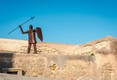 Full length of man standing on landscape against clear blue sky