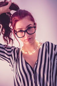 Young woman with illuminated string light against blue background