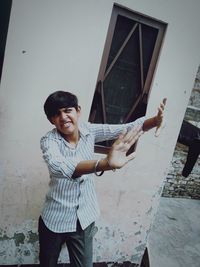 Full length of young man standing against wall