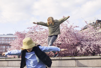 Girls jumping, blossoming cherry trees on background