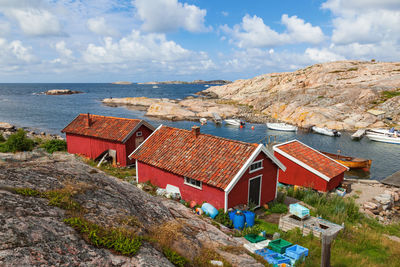 Houses on beach by buildings against sky