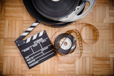 High angle view of film slate and reel on hardwood floor