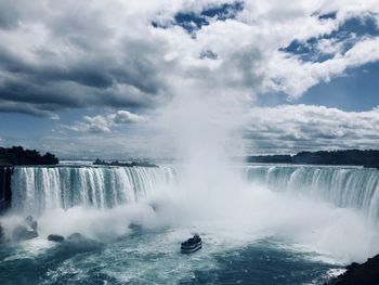 View of waterfall against cloudy sky