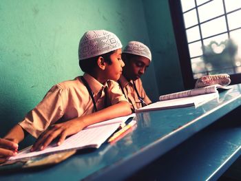 Close-up of students sitting on bench while studying at school