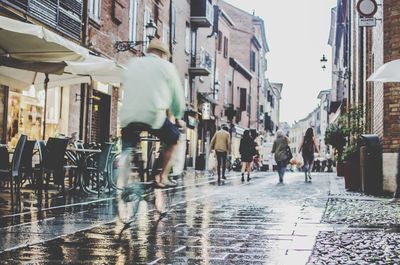 Blurred motion of man riding bicycle on wet road in city