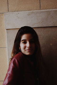 Portrait of beautiful young woman standing against wall