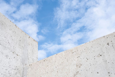 Low angle view of concrete wall against cloudy sky