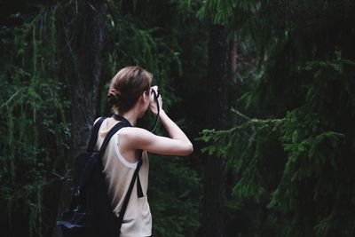 Side view of woman taking photo against plants