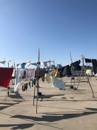 Lounge chairs on sand against clear blue sky on sunny day