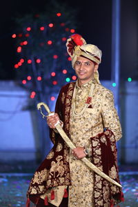 Portrait of bridegroom holding sword during wedding ceremony