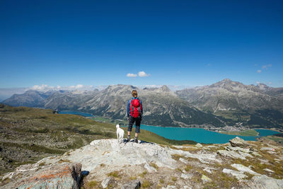 Rear view of woman looking at mountains against blue sky