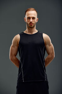 Portrait of young man standing against black background