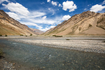 Scenic view of road by mountains against sky