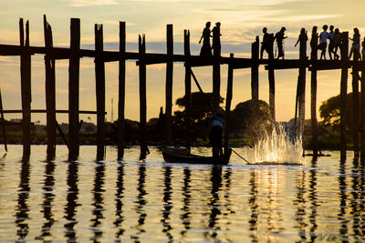 Silhouette people on lake against sky during sunset