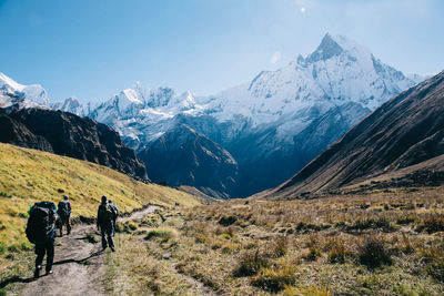 Rear view of people walking towards mountain during winter