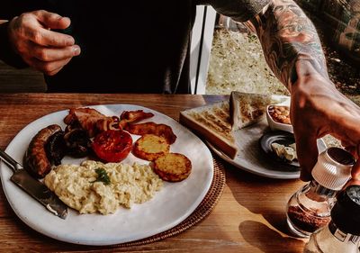 Close-up of tattooed man enjoying traditional english breakfast