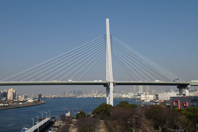 Suspension bridge over river against clear sky