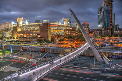 Light trails on road by buildings against sky in city