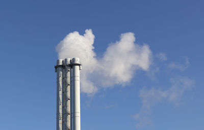 Low angle view of smoke emitting from chimney against sky