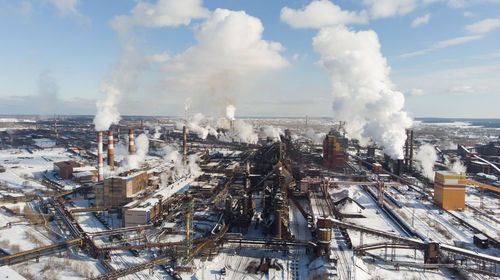 Panoramic view of smoke emitting from factory during winter