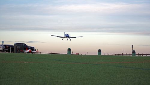 Airplane flying over field against sky