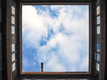 Man against cloudy sky seen through window