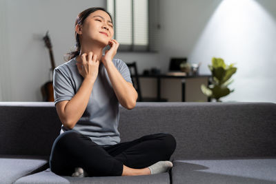 Young woman looking away while sitting at gym