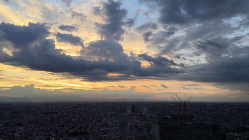 Aerial view of cityscape against cloudy sky