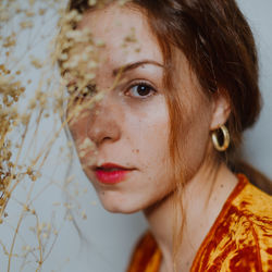 Close-up portrait of young woman by dried plant