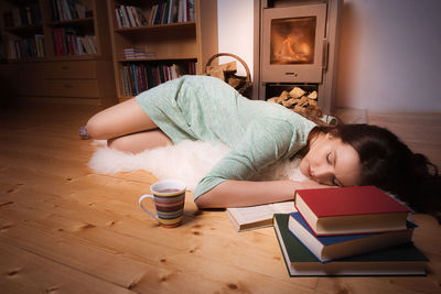 Young woman sleeping by books at home