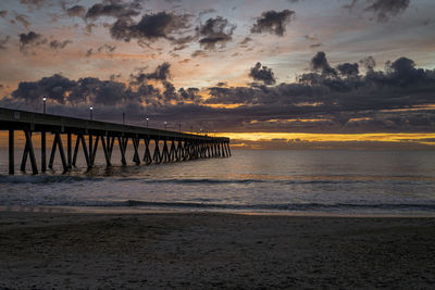 Pier over sea against sky during sunset