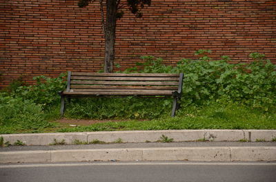 Empty bench against brick wall