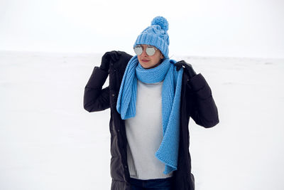 Girl running in a snowy field in a jacket and sunglasses