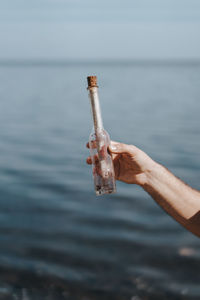 Person holding message in the bottle at sea shore
