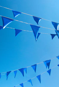 Low angle view of bunting flags against clear blue sky