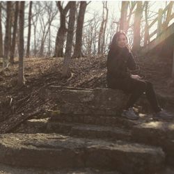 Woman sitting on tree trunk in forest