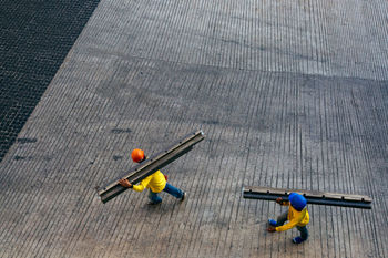 High angle view of workers carrying girder on street