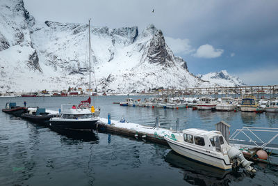 Boats moored in sea against sky during winter