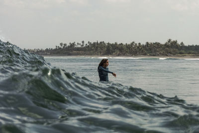 Woman in sea against sky