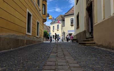 People walking on footpath amidst buildings in city