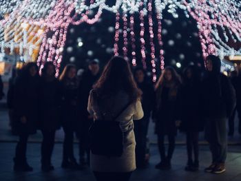 Rear view of woman with backpack photographing friends at party