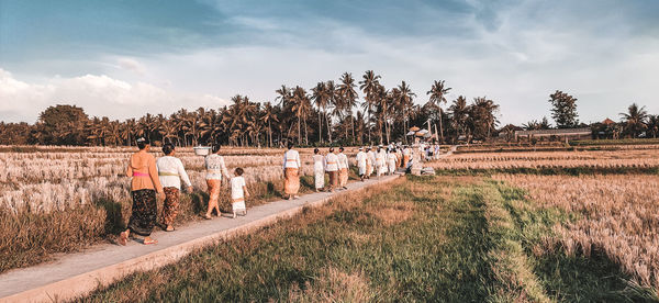 Rear view of people on field against sky