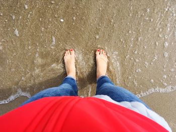 Low section of man on wet sand at beach