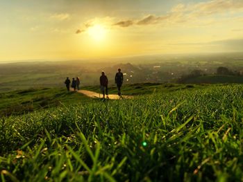 People on field against sky during sunset