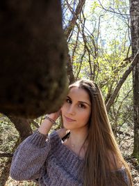 Portrait of smiling young woman against tree trunk