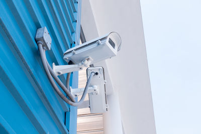 Low angle view of security camera mounted on wall