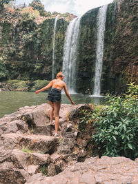 Full length of woman standing against waterfall